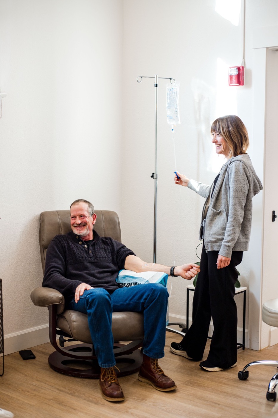A patient laughing in a recliner while a Swiftwater nurse adjusts his IV drip