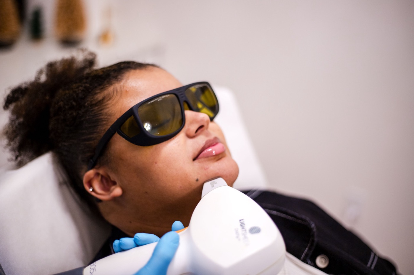 A smiling patient with a deeper skin tone having laser hair removal on her chin with the LightSheer