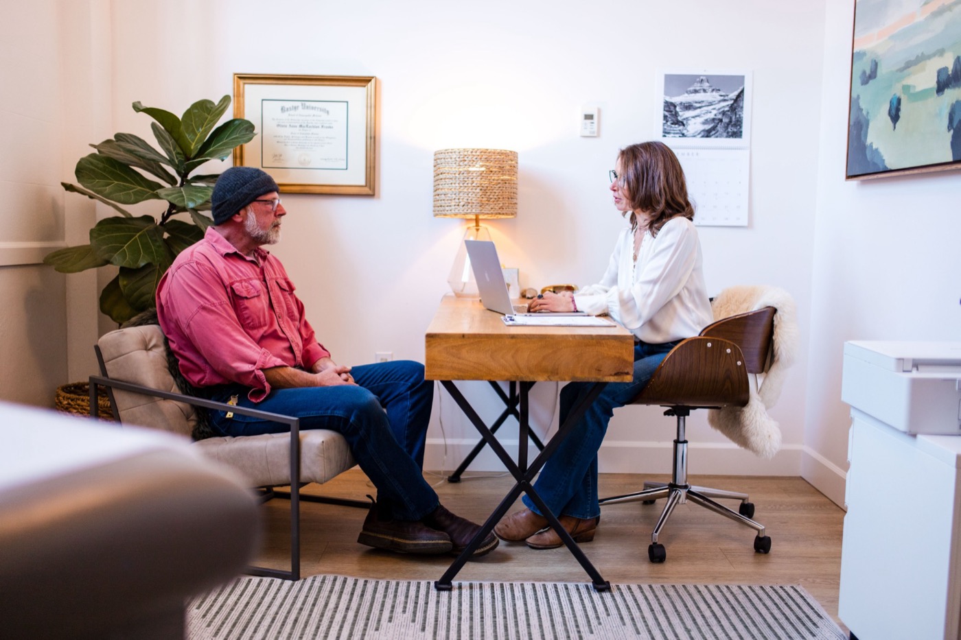 Dr. Franks talking with a patient in her office beneath her naturopathic medicine diploma
